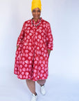 Model wearing red dress with pink flower print.