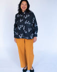 Model wearing black long sleeved shirt with white music print design.