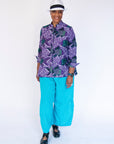 Model wearing long sleeved shirt with purple and green fish print.