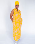 Model wearing yellow sleeveless dress with abstract pink print.