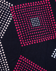 Close up display of pink, orange, white and black geometric print dress, fabric.