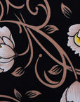 Close up display of black dress with pink and yellow floral print, fabric