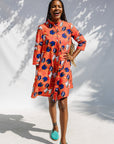 Model wearing yellow and red, blue book print dress.