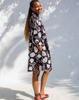 Model wearing black dress with pink and yellow floral print.
