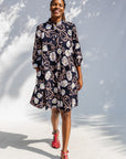 Model wearing black dress with pink and yellow floral print.