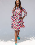 Model wearing white dress with yellow, red and blue bug print.