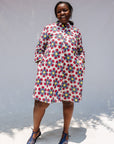 Model wearing white dress with yellow, red and blue bug print.