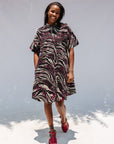 Model wearing pink, black and white glitter print dress