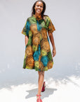 Model wearing black dress with orange, yellow, blue and green swirls.