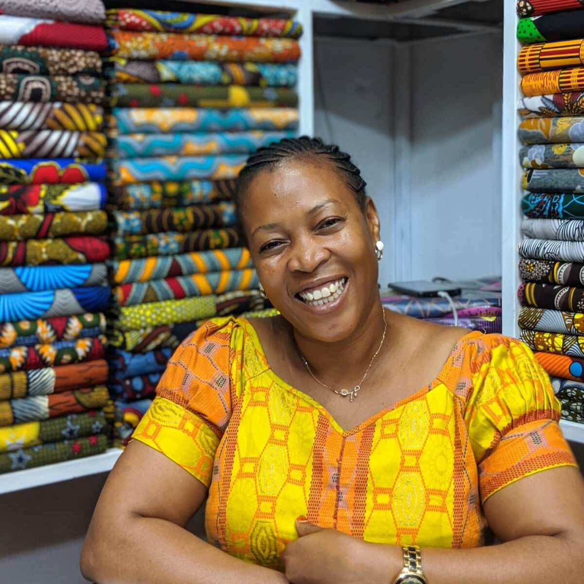 Woman standing in front of a colorful display of fabric in a store.