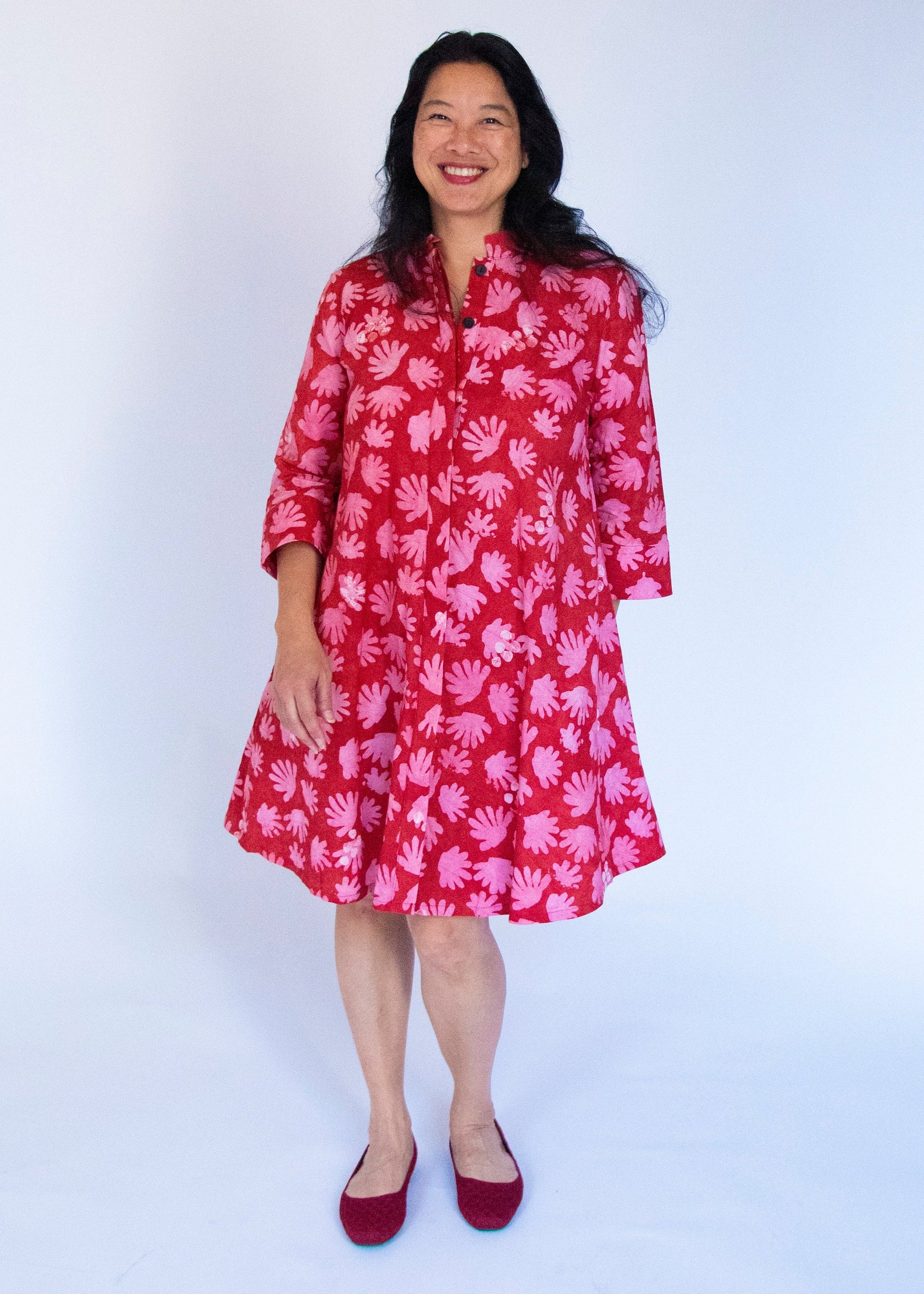 Model wearing red dress with pink flower print.