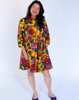 Model wearing yellow dress with multicolor floral print.