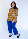 Model wearing long sleeved orange and purple geometric print shirt.