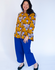 Model wearing long sleeved orange and purple geometric print shirt.