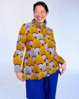 Model wearing long sleeved orange and purple geometric print shirt.
