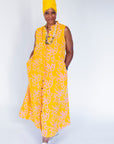 Model wearing yellow sleeveless dress with abstract pink print.