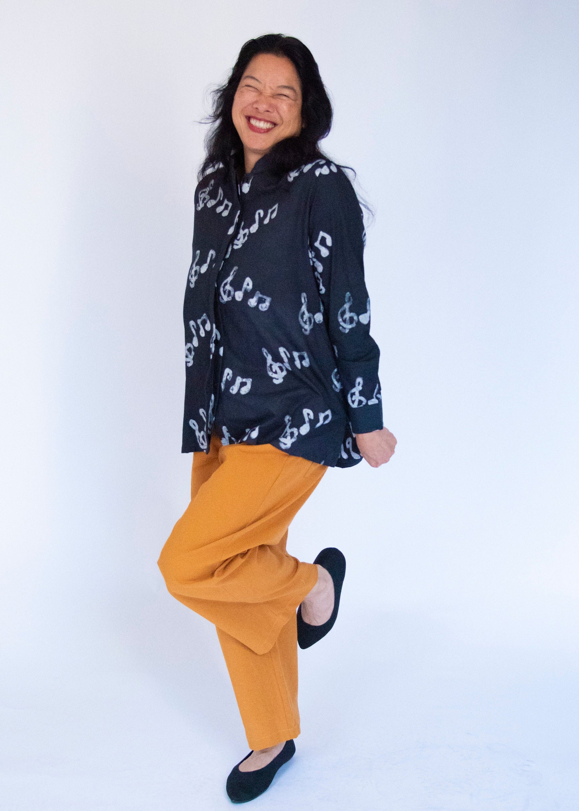 Model wearing black long sleeved shirt with white music print design.