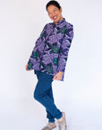 Model wearing long sleeved shirt with purple and green fish print.