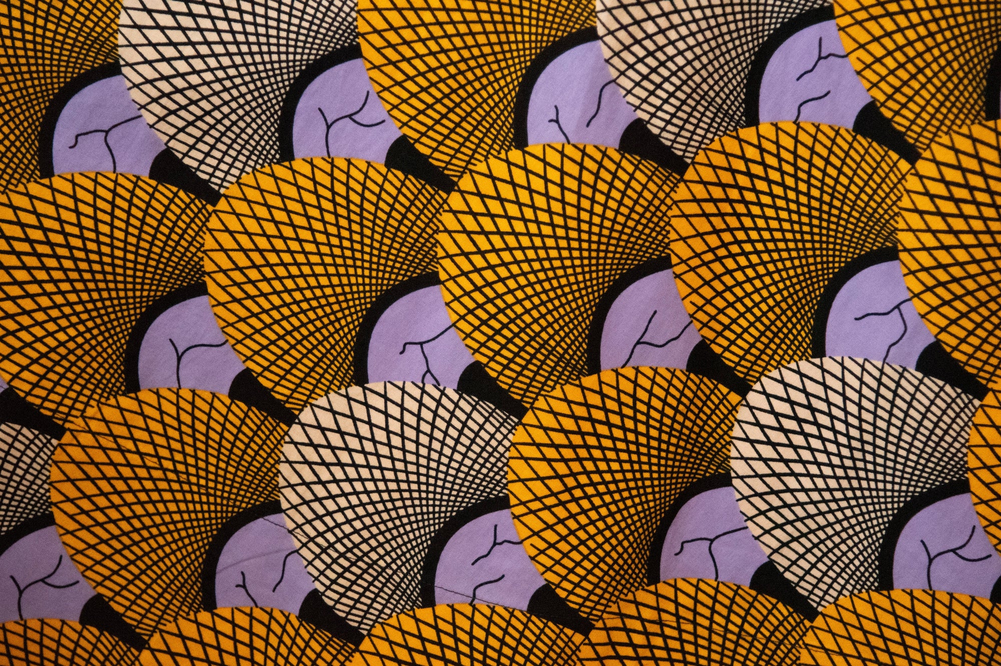 Close up display of long sleeved orange and purple geometric print shirt, fabric.