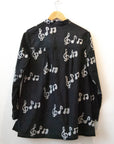 Display of black long sleeved shirt with white music print design.