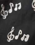 Close up display of black long sleeved shirt with white music print design, fabric.