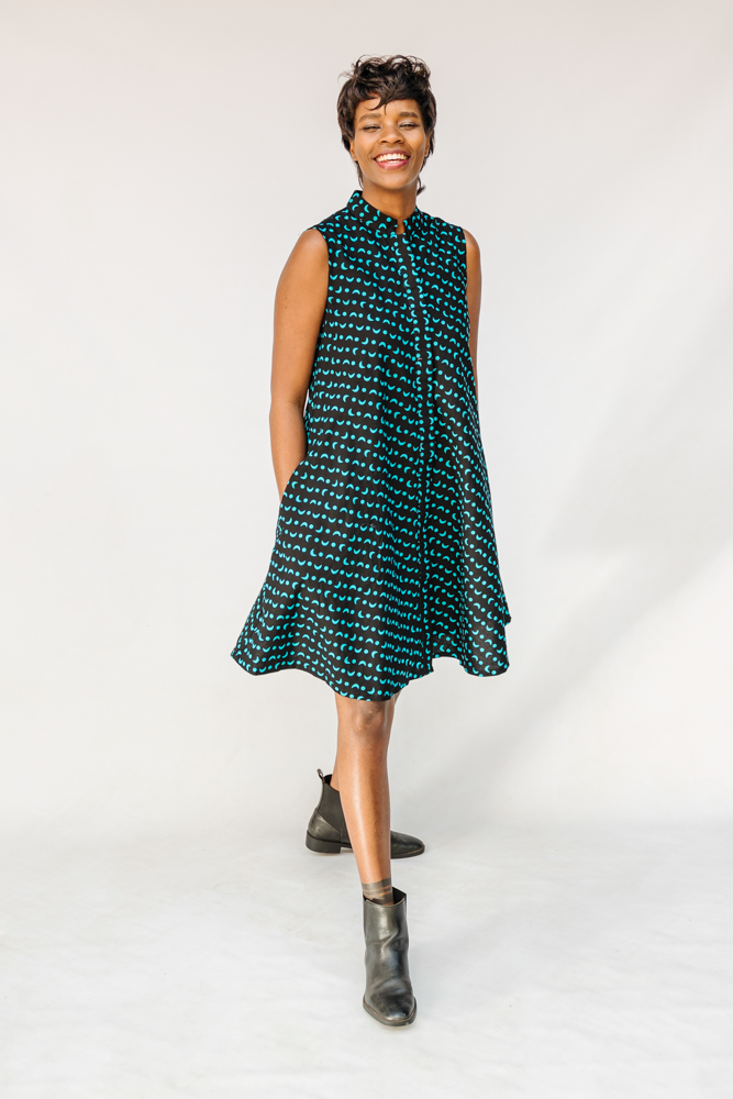 Model wearing sleeveless black dress with teal moon design.