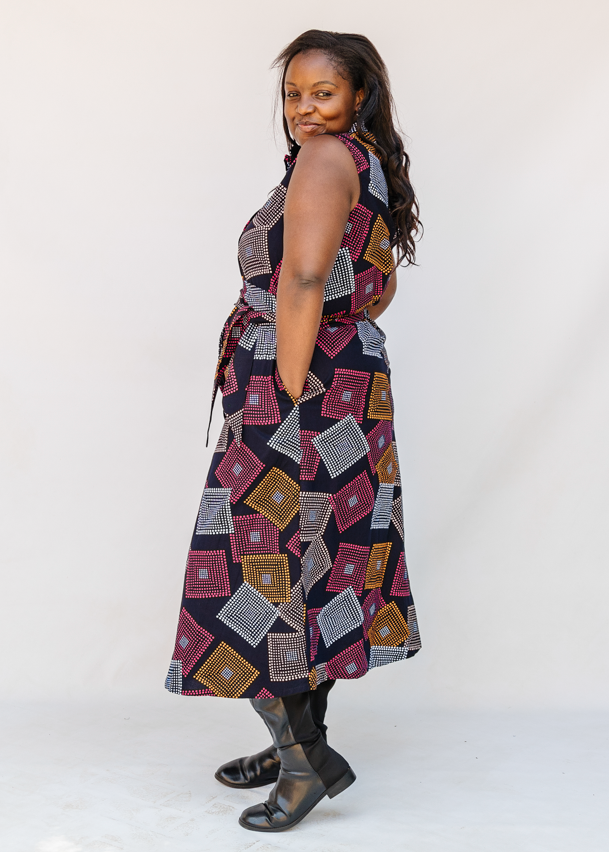Model wearing pink, orange, white and black geometric print dress.