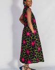 Model wearing navy and green dress with pink floral print.