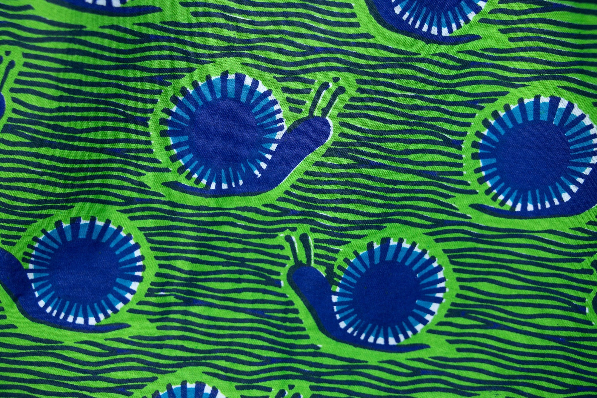 Close up display of sleeveless dress with green and blue snail print.