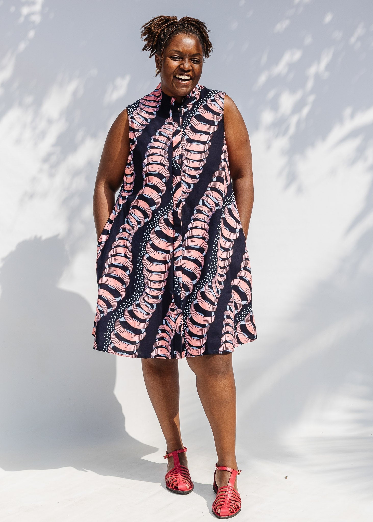 Model wearing black and pink sleeveless print dress.