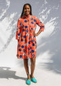 Model wearing yellow and red, blue book print dress.
