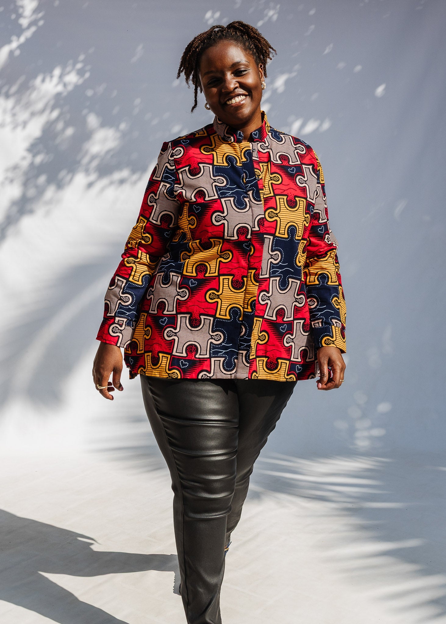 Model wearing multicolored puzzle print shirt.