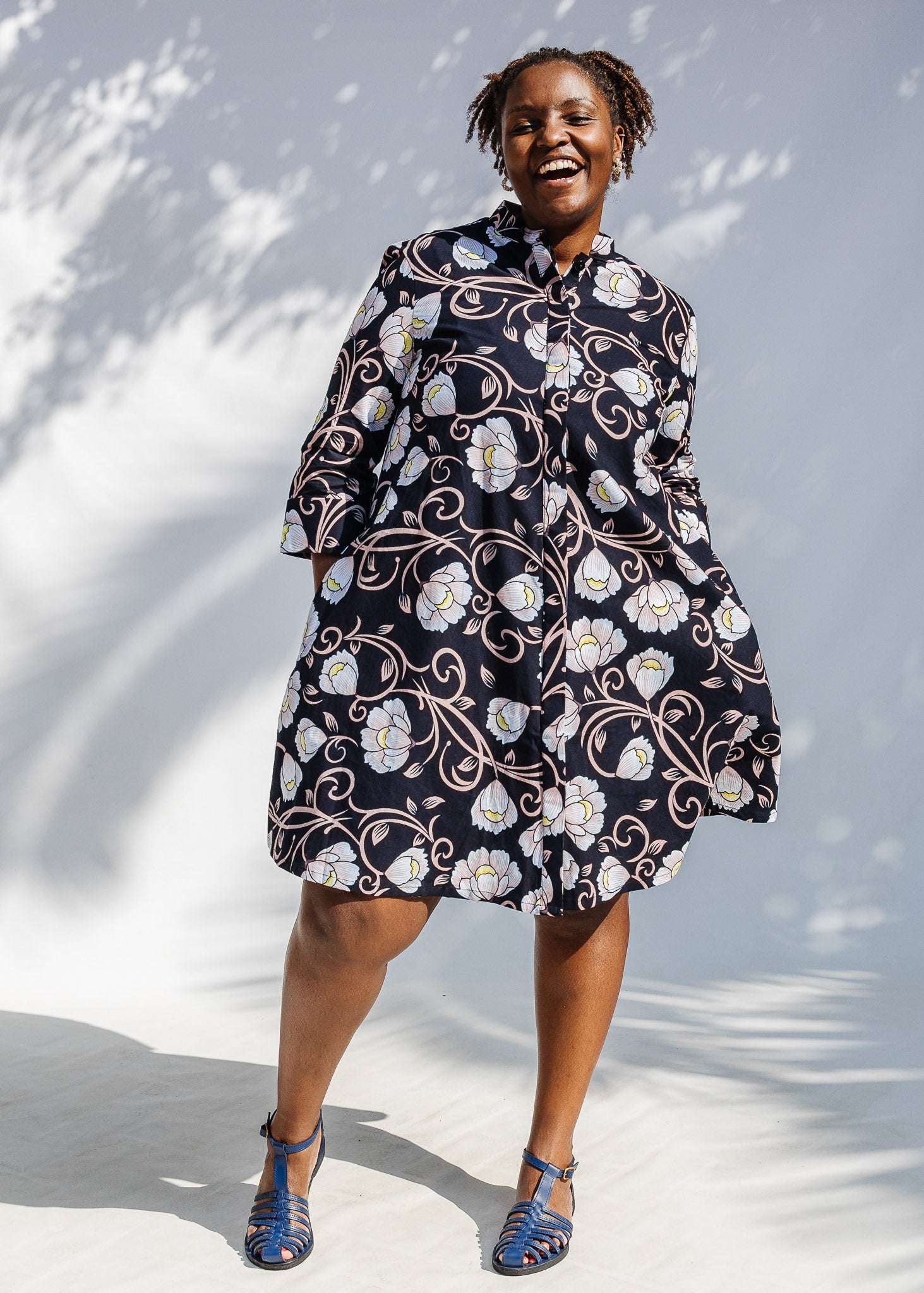 Model wearing black dress with pink and yellow floral print.