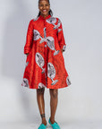Woman wearing a red patterned dress with teal shoes on a white background