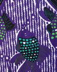 Close up display of long sleeved shirt with purple and green fish print, fabric.
