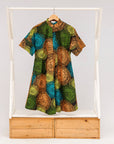 Display of black dress with orange, yellow, blue and green swirls.