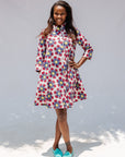 Model wearing white dress with yellow, red and blue bug print.