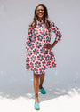 Model wearing white dress with yellow, red and blue bug print.
