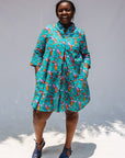 Model wearing teal dress with pink and orange shrimp print.