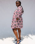 Model wearing white dress with yellow, red and blue bug print.