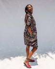 Model wearing pink, black and white glitter print dress