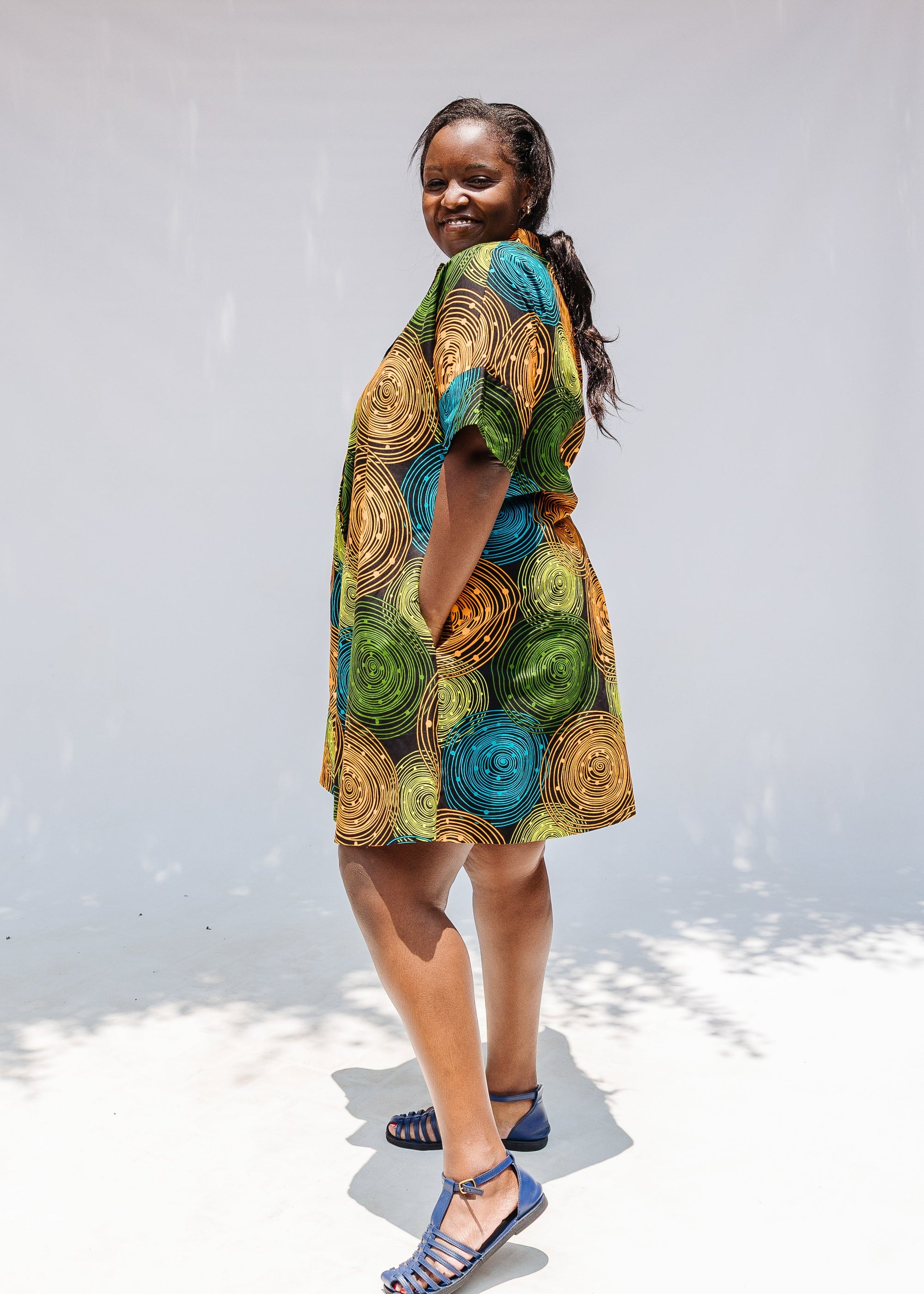 Model wearing black dress with orange, yellow, blue and green swirls.