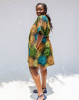 Model wearing black dress with orange, yellow, blue and green swirls.
