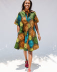 Model wearing black dress with orange, yellow, blue and green swirls.